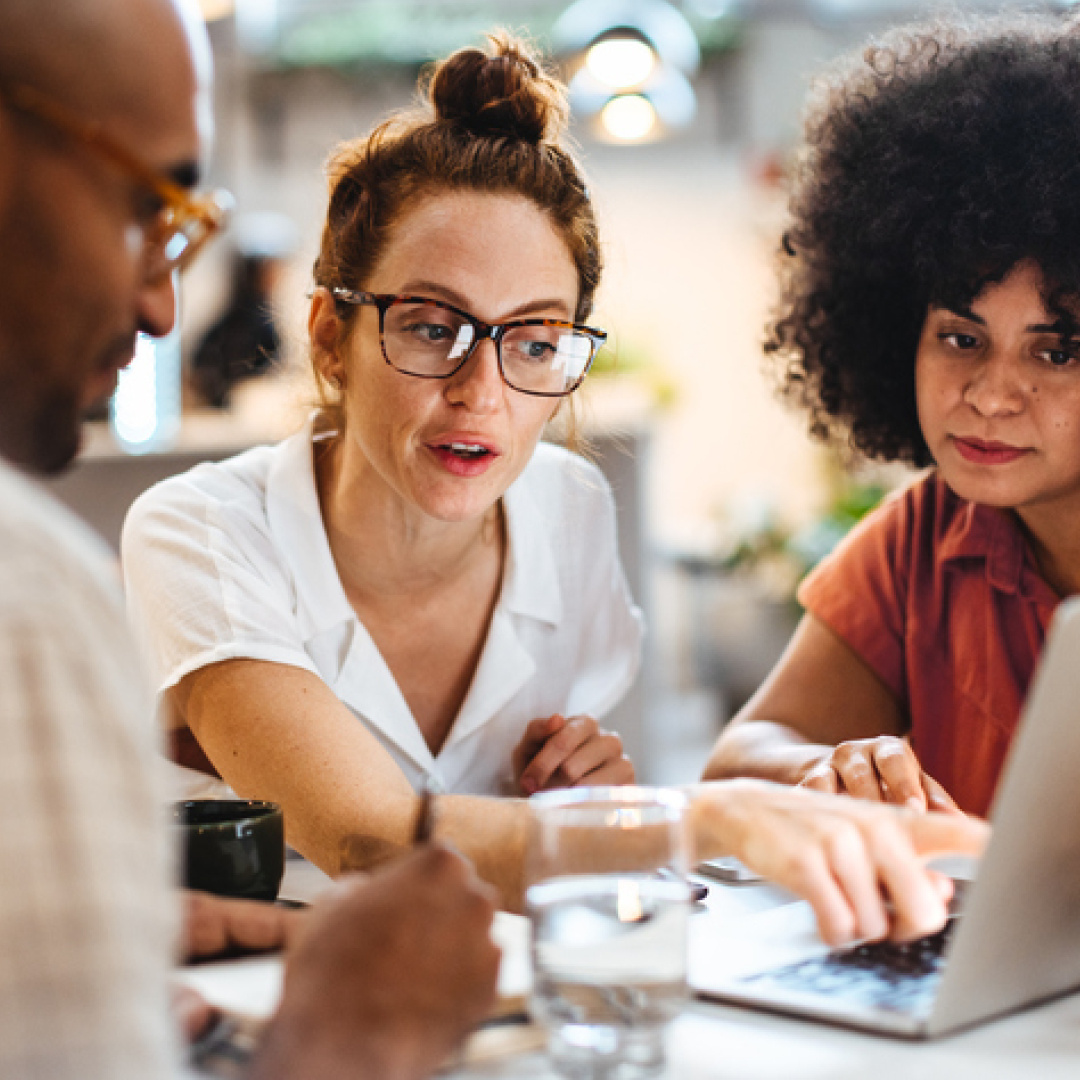 Woman pointing at laptop with colleagues